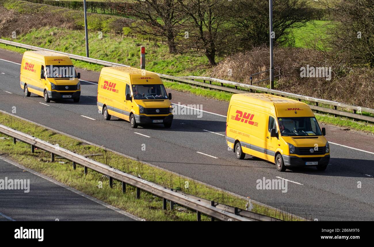 DHL International Shipping; Drei gelbe Transport-Lieferwagen, Lkw, Transport, Frachtführer, Deutsche Post DHL Vehicle, Commercial Transport, Industry, M6 in Manchester, Großbritannien Stockfoto