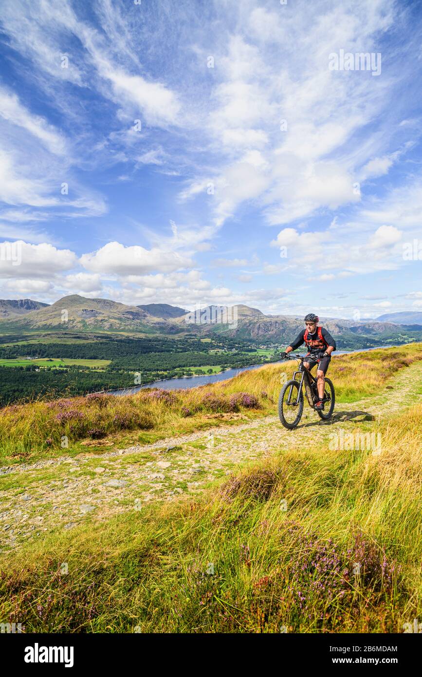 Radfahrer (auf E-Bike) auf dem Grat von Park Crags, mit Coniston Water und dem Coniston Fells im englischen Lake District Stockfoto