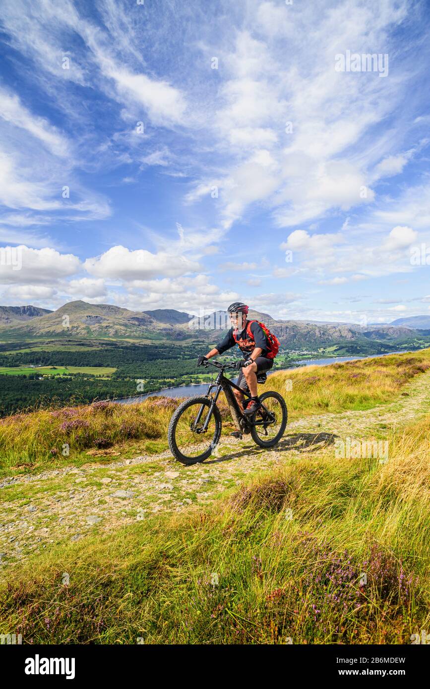 Radfahrer (auf E-Bike) auf dem Grat von Park Crags, mit Coniston Water und dem Coniston Fells im englischen Lake District Stockfoto