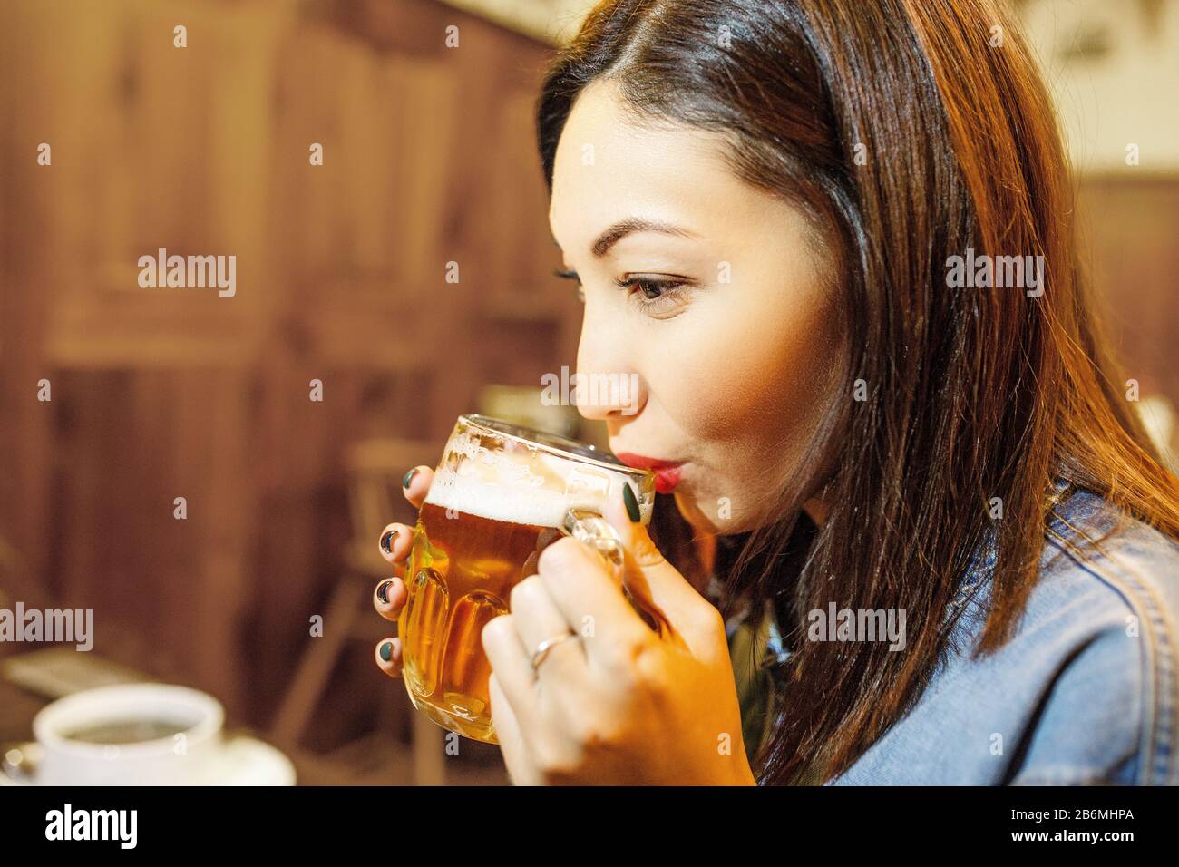 Schöne Brünette Ostfrau trinkt leichtes Handwerker-Bier in der Bar Stockfoto
