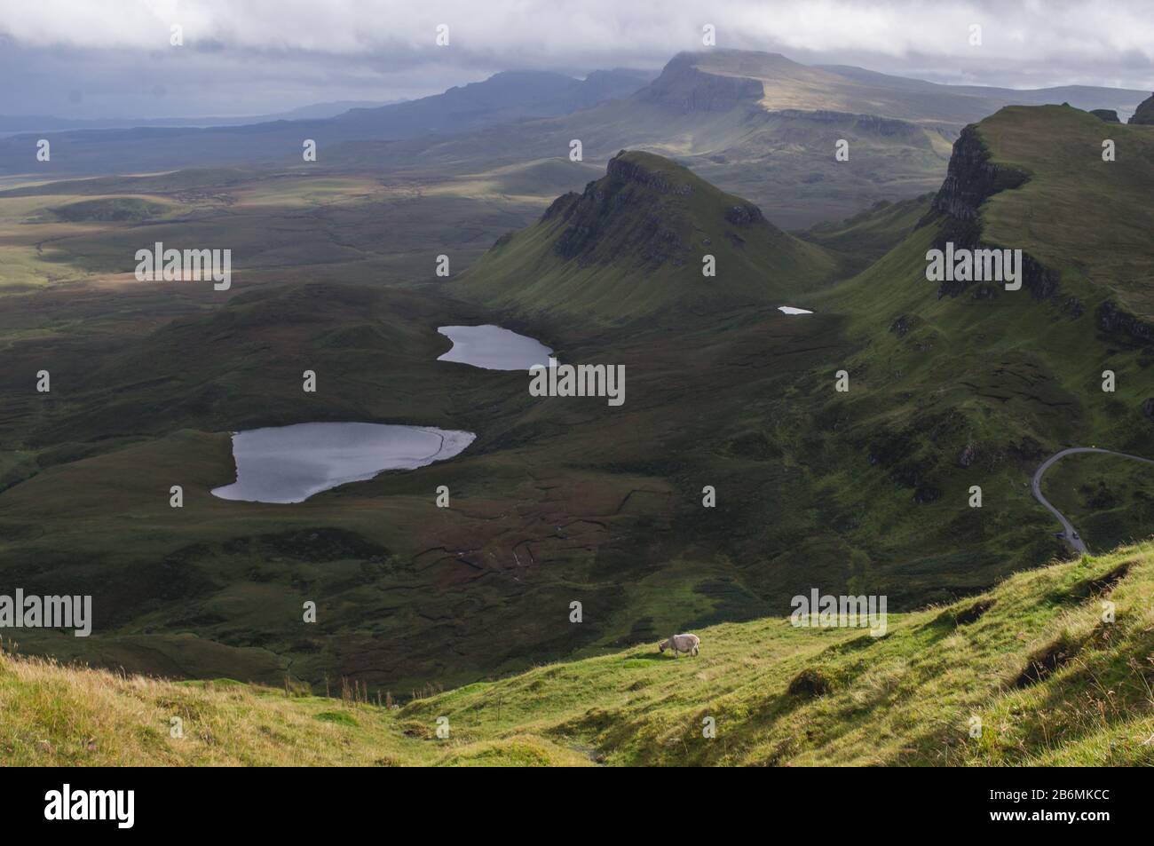 Lange kurvenreiche Straße bei Quiraing auf der Insel Skye mit einem wunderschönen, lebendigen schottischen Himmel. Stockfoto