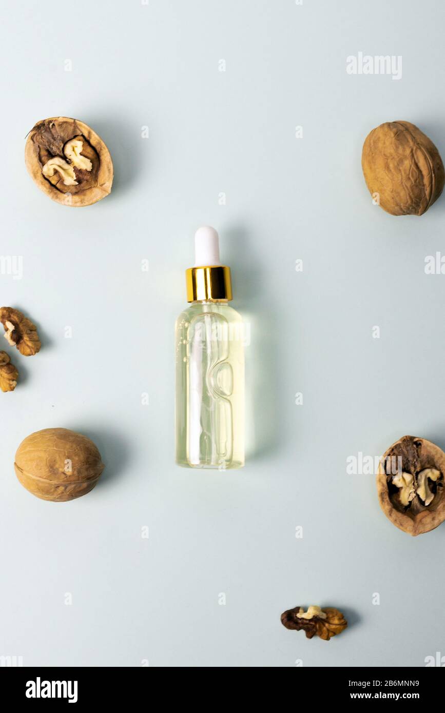 Kosmetik- und Heilöl aus Nussbaum auf blauem Pastellgrund. Nussbaum kosmetisches Feuchtigkeitsspendende Serum. Das Konzept der natürlichen Inhaltsstoffe in der Kosmetik. Stockfoto