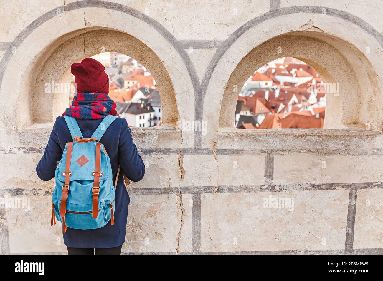 Fröhliche junge Frau mit Rucksack, die im Winter in Cesky Krumlov unterwegs ist Stockfoto