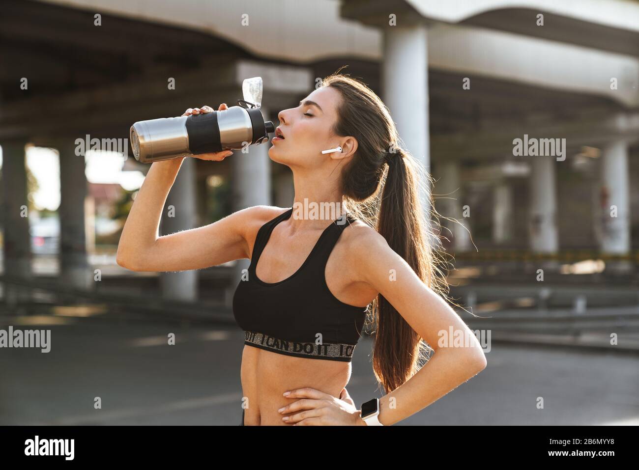 Bild einer ernsthaften Sportfitness Frau im Freien Musik hören mit Ohrhörern Trinkwasser. Stockfoto