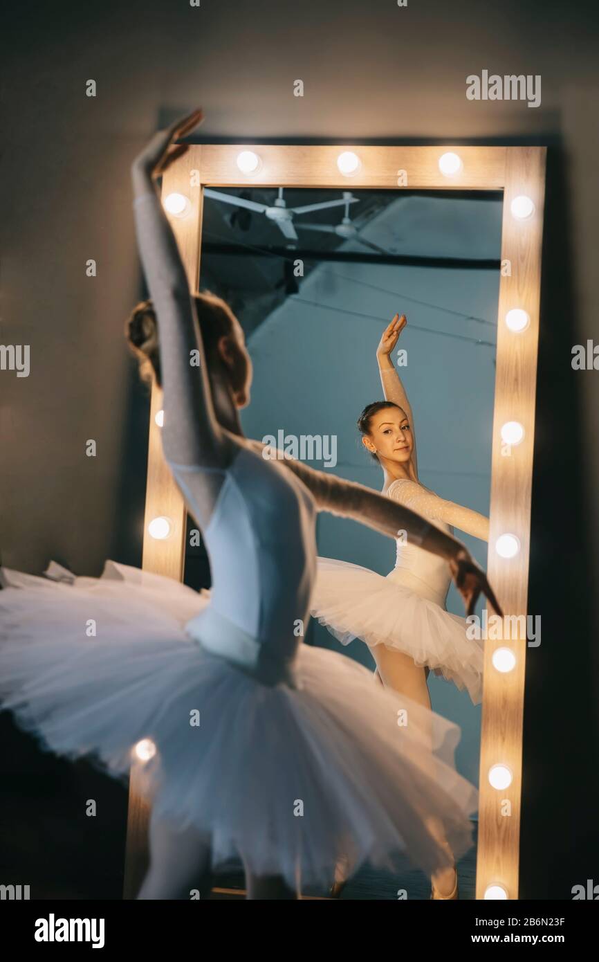 Junge Ballerina in weißem Kleid mit perfektem Körper tanzt im Studio Stockfoto