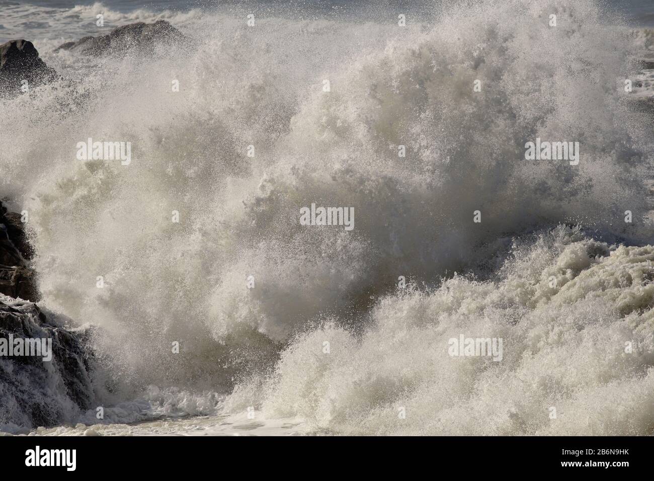 An einem sonnigen Tag spritzt die stürmische Meereswelle. nordportugiesische Felsküste. Stockfoto