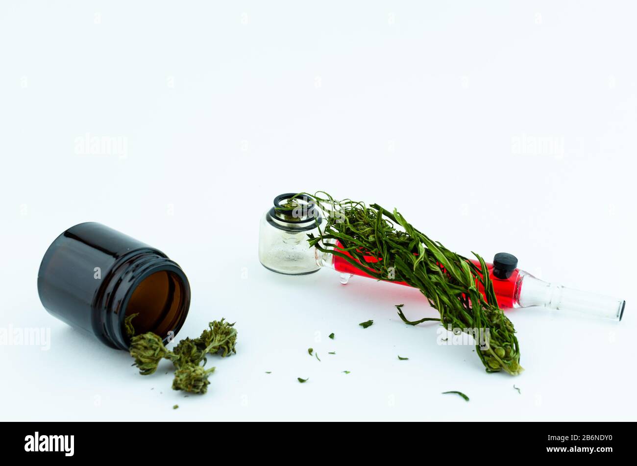 Schwarze medizinische Glasflasche mit Cannabisknospen im Inneren und gläsernes Smoking Pipe im Hintergrund. Medizinisches Cannabiskonzept Stockfoto