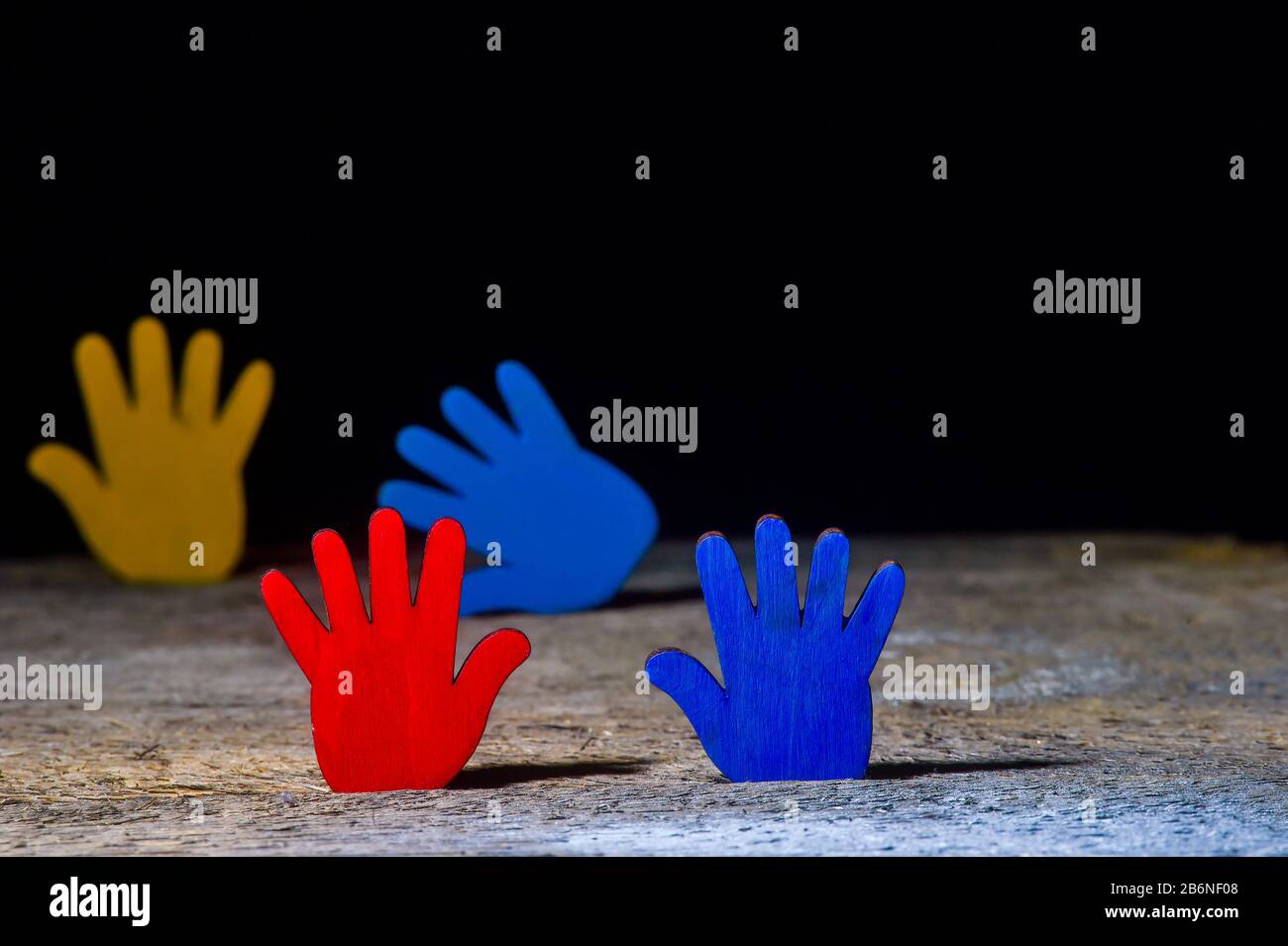 Farbige Puzzles Hände auf schwarzem Hintergrund. Weltautism Awareness Day Konzept Stockfoto