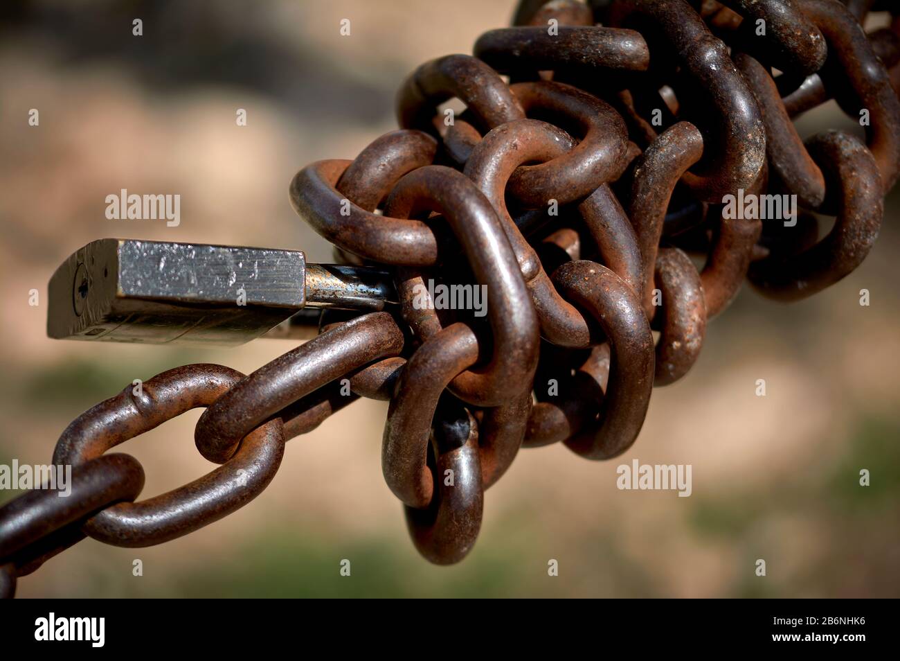 Detail einer verdrehten Metallkette mit einem Vorhängeschloss im Freien Stockfoto