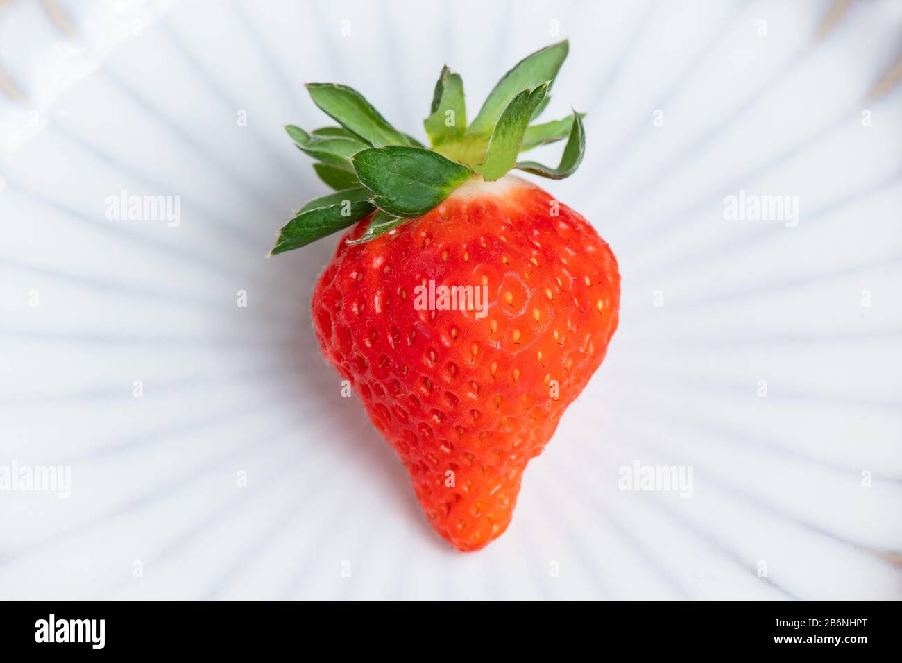 Eine frische Erdbeere auf weißem Porzellanteller, Stockfoto