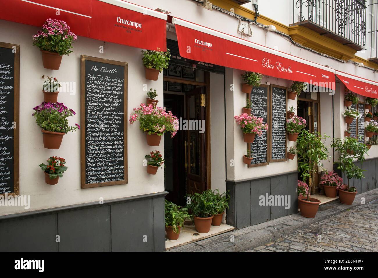 Blumentöpfe und Speisekarte der Estrella Tapas Bar in der Estrella St, Sevilla, Spanien Stockfoto