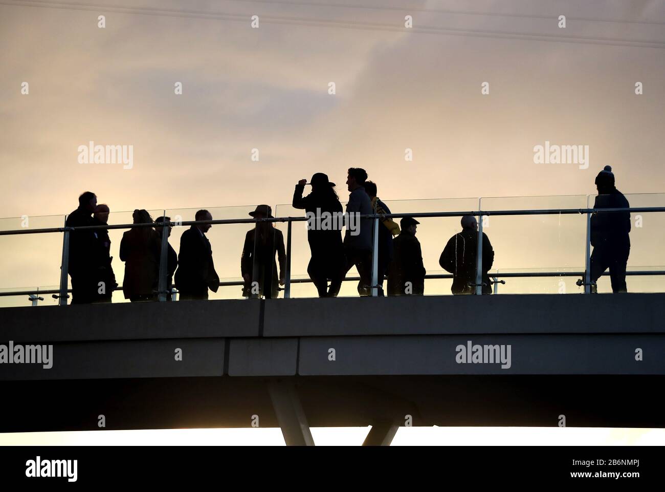 Racegoers gehen am Ende des zweiten Tages beim Cheltenham Festival auf der Rennbahn Cheltenham über die Brücke. Stockfoto