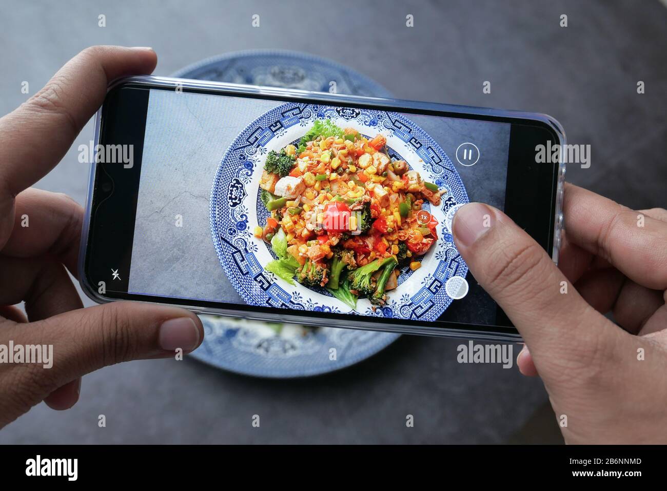 Mädchen fotografieren mit ihrem Smartphone vegetarische Speisen auf dem Tisch. Stockfoto
