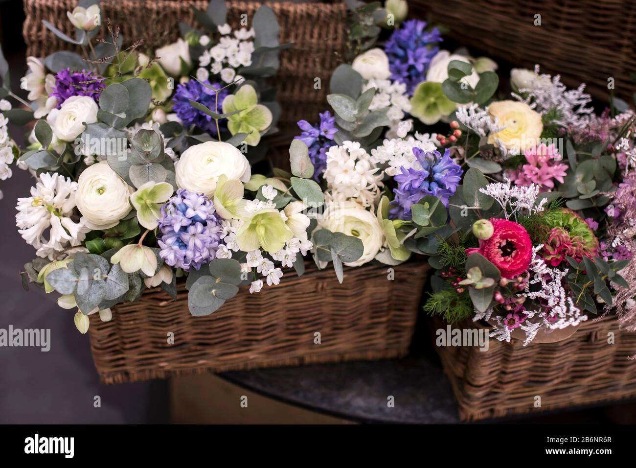 Blumenstrauß aus weißem Ranunculus, rotem Gänseblümchen, Eukalyptus, blauen Hyazinths, weißer Kirsche in einer Weidenschachtel zum Verkauf Stockfoto