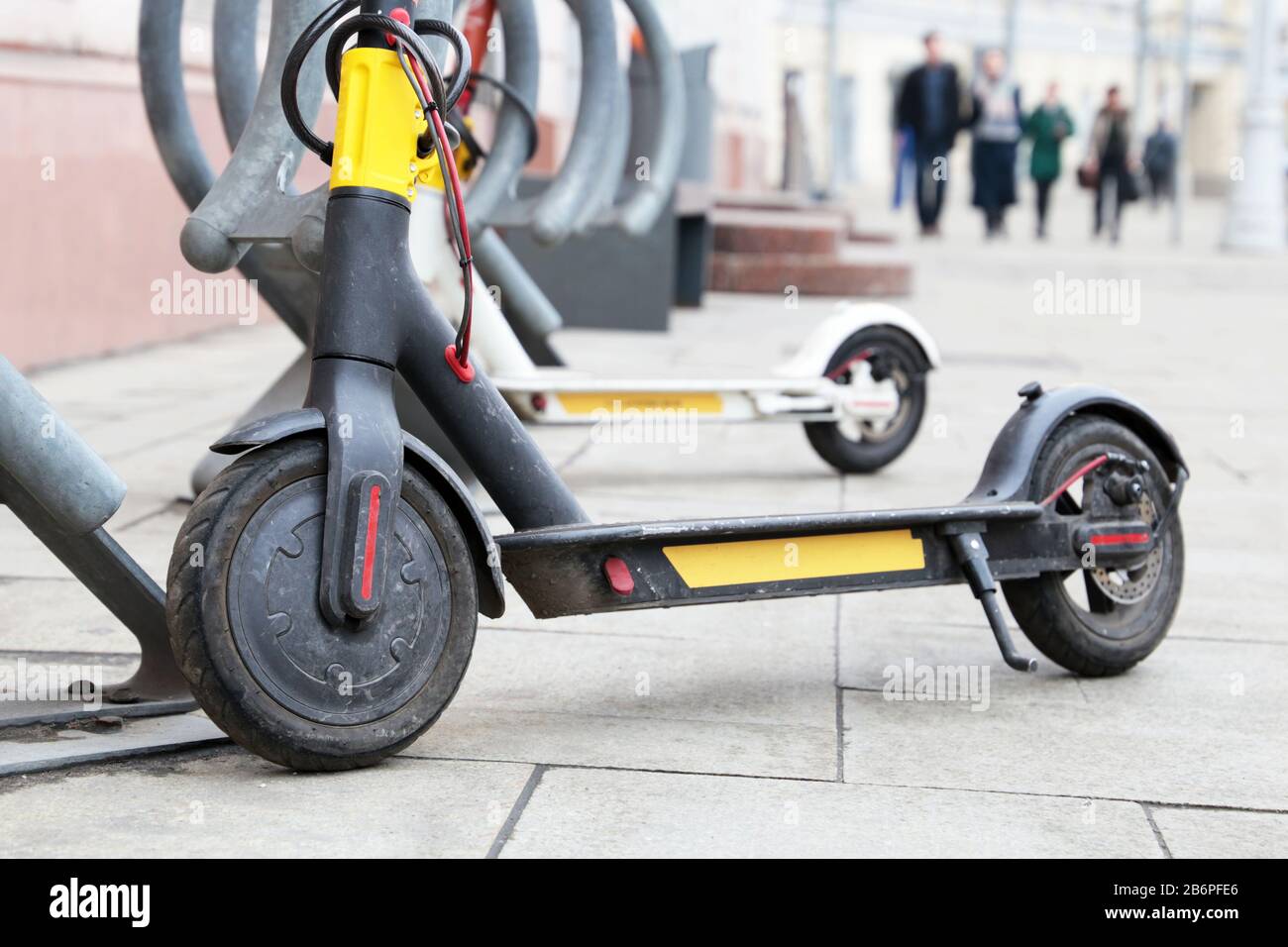 Elektrische Roller hintereinander auf dem Parkplatz. Stadtradverleih, öffentliche E-Roller auf der Straße Stockfoto