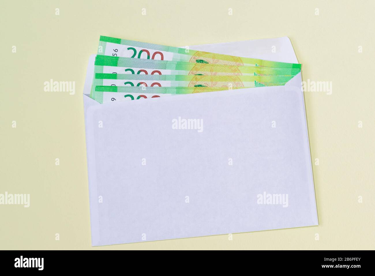 Weißer Umschlag mit Geld auf gelbem Hintergrund. Geldbestellung Stockfoto