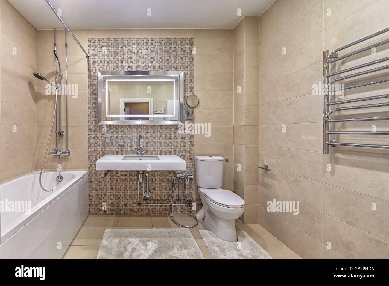 Modernes Bad, Spiegel, toilette und Keramikwaschbecken in beigefliesten geräumigen, sauberen Badezimmern Stockfoto
