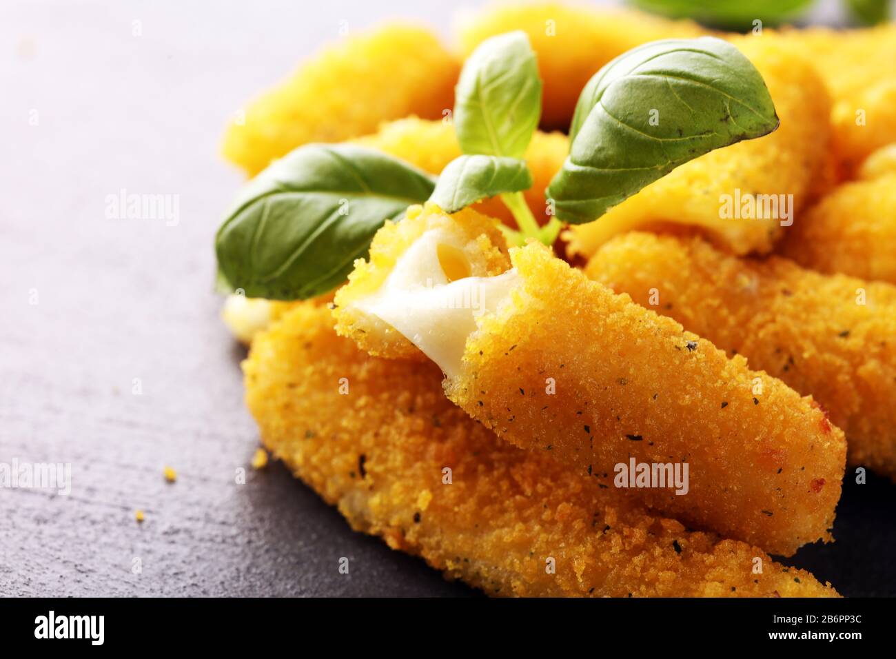 Panierte Mozzarella-Käsestäbchen mit Basilikum auf dem Tisch Stockfoto