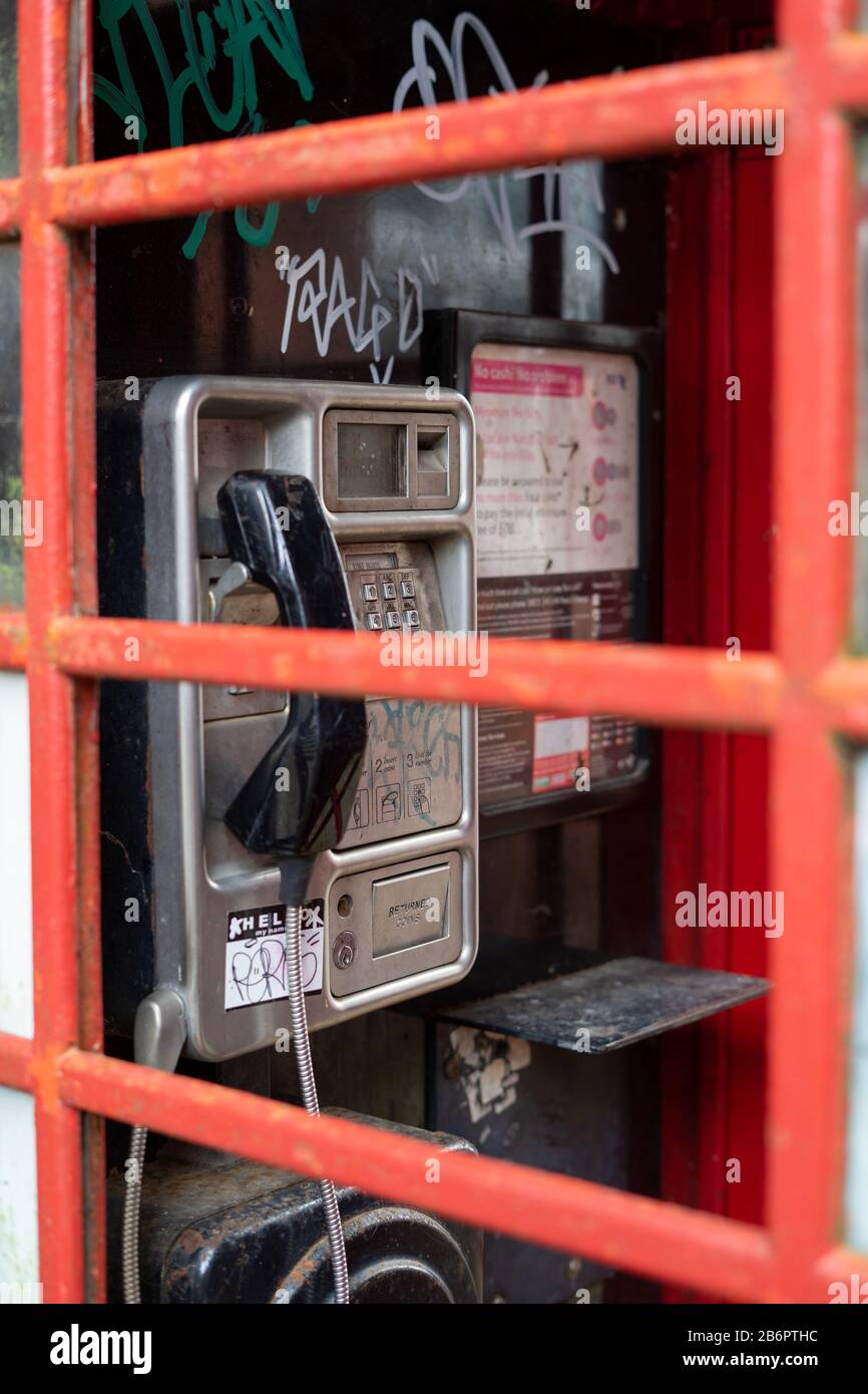 Eine alte Telefonbox schoss durch das zerbrochene Glas der roten Telefonbox, nachdem sie vandalisiert war Stockfoto