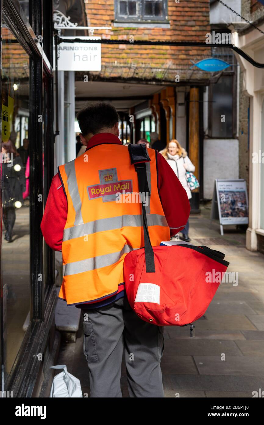 Ein Postbote von Royal, der Post auf der Straße mit einem Postsack auf der Schulter liefert Stockfoto