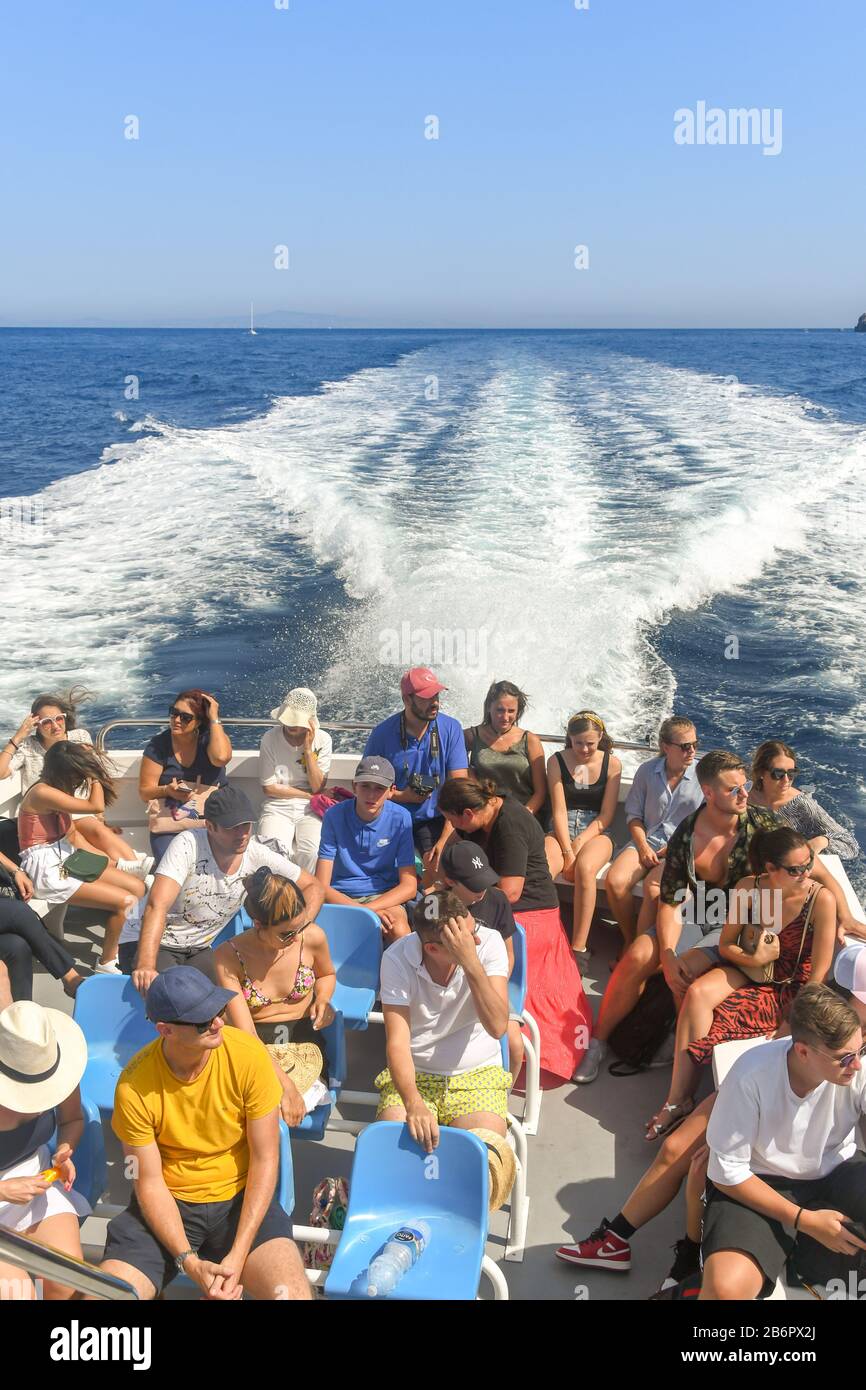Insel CAPRI, ITALIEN - AUGUST 2019: Gruppe von Menschen, die auf der Rückseite eines Schnellboots vor der Insel Capri sitzen. Stockfoto