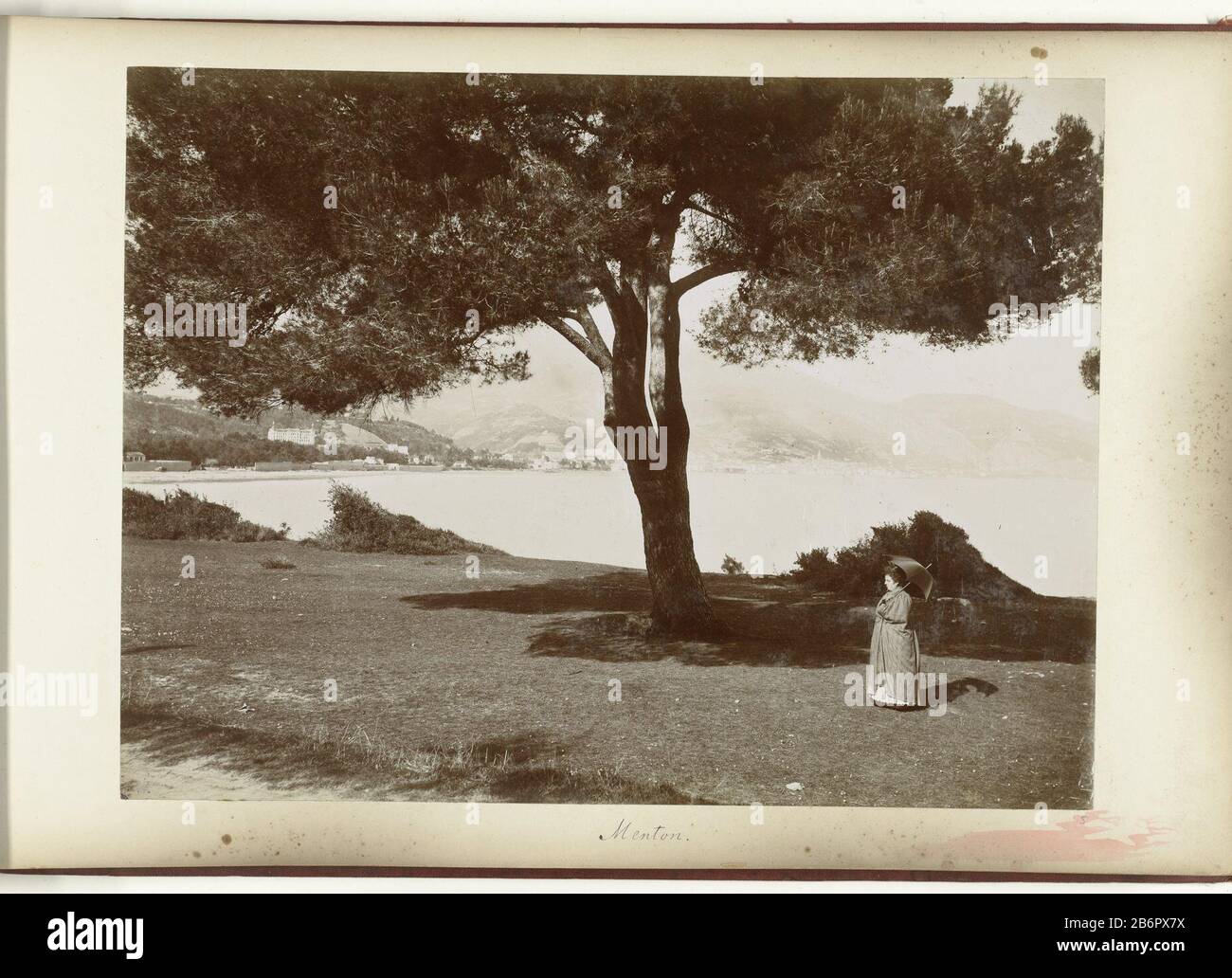 Gezicht op de kuststrook van Menton traf nabij gelegen plaatsen Menton (titel op object) Blick auf die Küste von Menton auf dem Rasen im Vordergrund ein großer Baum und eine Dame mit Sonnenschirm. Hersteller : Fotograf: Henry Peacock Wer: Ldrecht (möglich) Herstellung: Frankreich Datum: CA. Von ca. Technische Merkmale: Albumindrucke auf Fotopapier auf Karton Albuminmaterial: Papierkartontechnik: Albumdruck Format: Foto: H 287 mm × W 374 mmblad: H 322 mm × W 498 mmOnderwerp Stockfoto