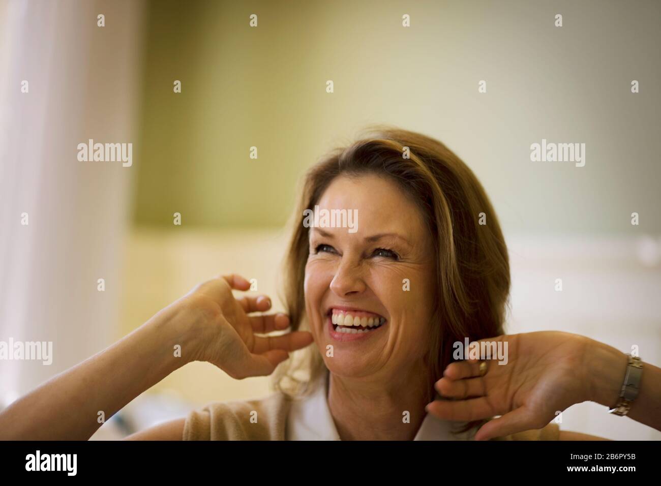 Erwachsene Frau, die mit erhobenen Händen lächelt. Stockfoto