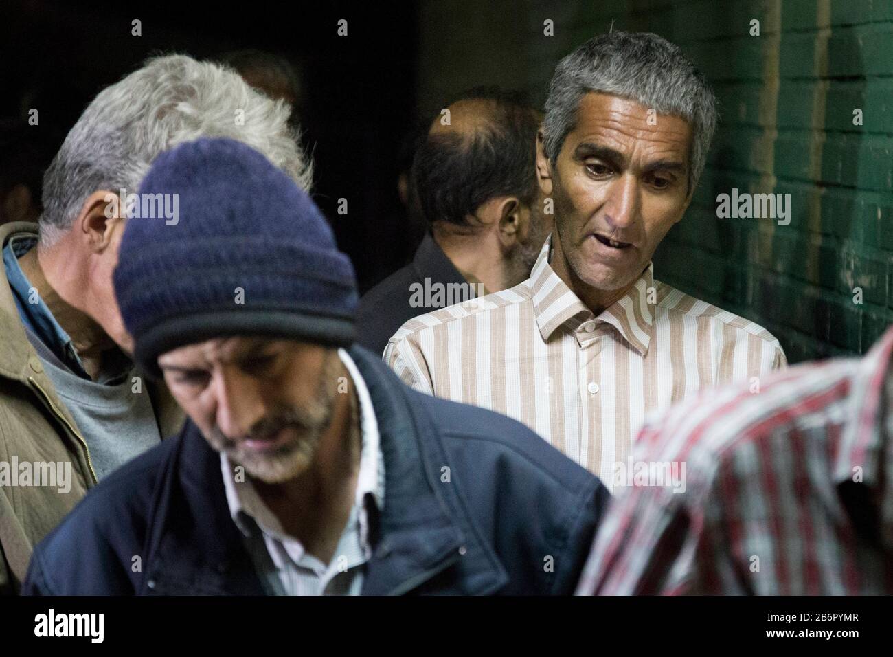 Teheran, Iran. März 2020. Obdachlose Männer stehen auf, während sie warten, von einem Mitarbeiter zu desinfizieren, bevor sie nach einem neuen Coronavirus (Covid-19)-Ausbruch im Iran in Khavaran Obdachlose Shelter im Süden Teherans eindringen. Die Khavaran-Halle soll 600 Personen beherbergen. Diese Kapazität wird in der Winternacht auf 1.100 ausgedehnt. In der Anlage sind auch Saisonarbeiter untergebracht, die duschen, eine warme Mahlzeit pro Tag essen und dort schlafen. Kredit: Zuma Press, Inc./Alamy Live News Stockfoto