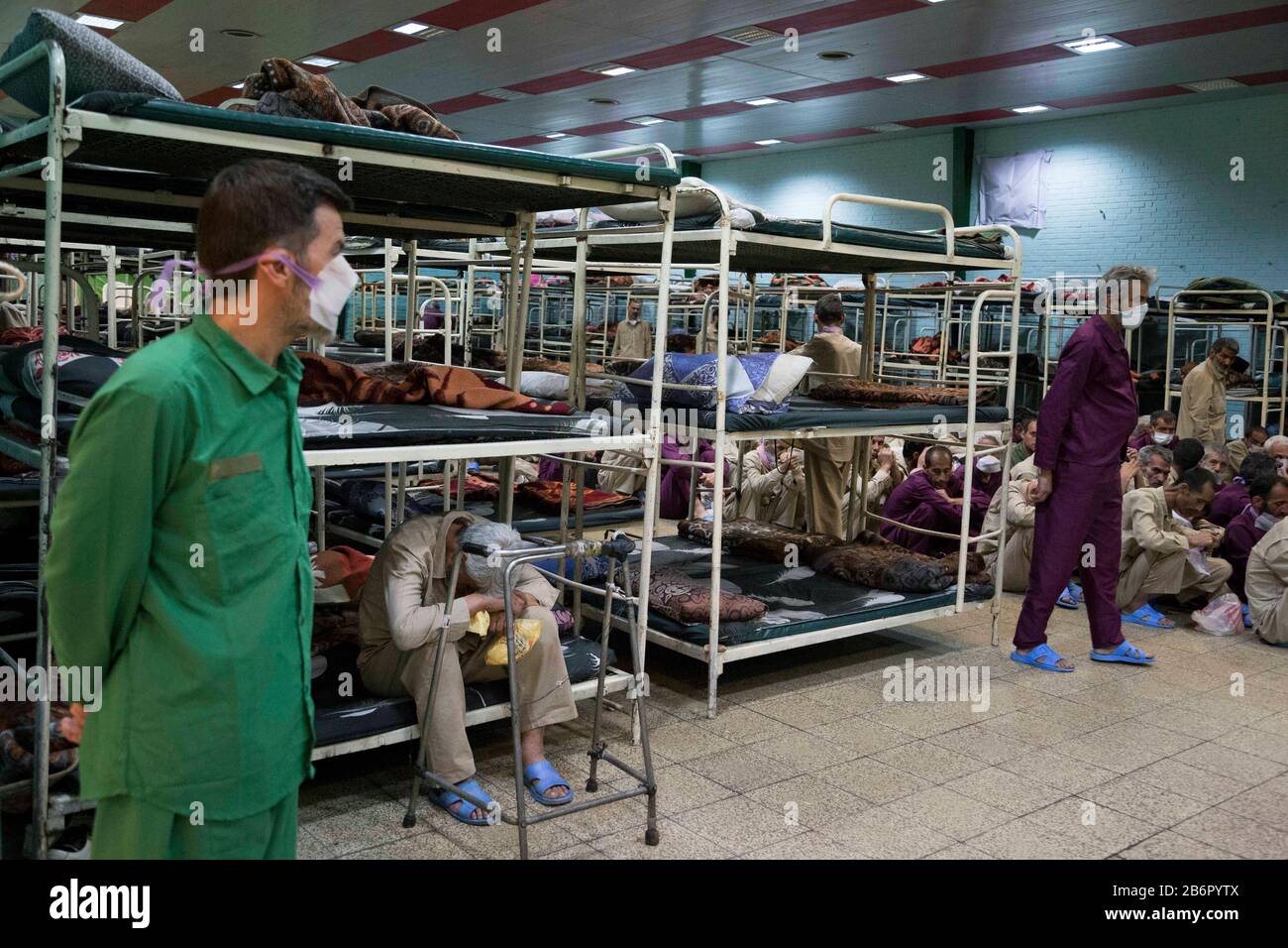 Teheran, Iran. März 2020. Obdachlose Männer, die Gesichtsschutzmasken und saubere Kleidung tragen, werden nach der Desinfektion und dem Duschen im Süden Teherans nach einem neuen Coronavirus (Covid-19) im Iran in Khavaran Obdachlose Obdachlosen gesehen. Die Khavaran-Halle soll 600 Personen beherbergen. Diese Kapazität wird in der Winternacht auf 1.100 ausgedehnt. In der Anlage sind auch Saisonarbeiter untergebracht, die duschen, eine warme Mahlzeit pro Tag essen und dort schlafen. Kredit: Zuma Press, Inc./Alamy Live News Stockfoto