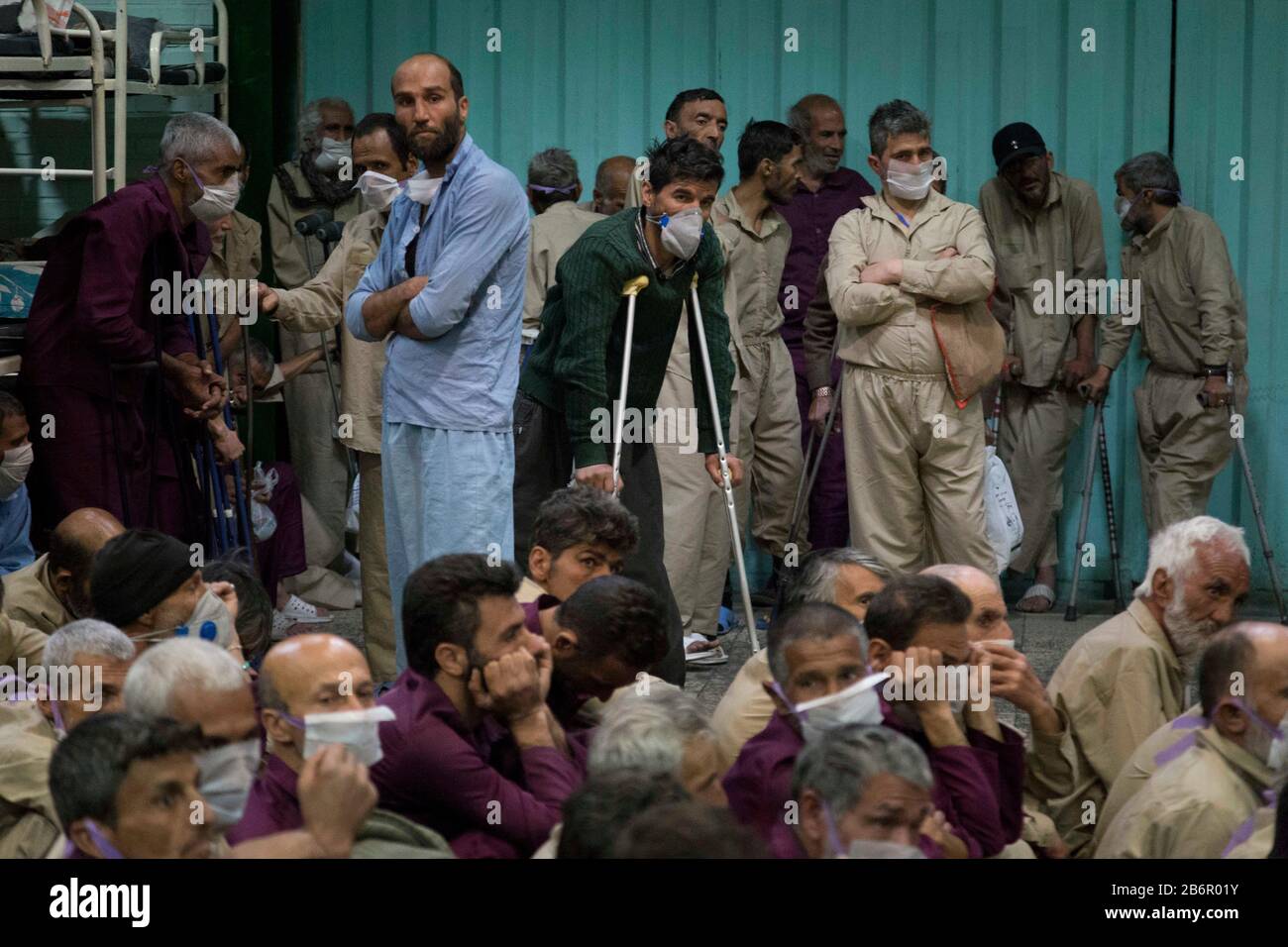Teheran, Iran. März 2020. Obdachlose Männer, die Gesichtsschutzmasken und saubere Kleidung tragen, werden nach der Desinfektion und dem Duschen im Süden Teherans nach einem neuen Coronavirus (Covid-19) im Iran in Khavaran Obdachlose Obdachlosen gesehen. Die Khavaran-Halle soll 600 Personen beherbergen. Diese Kapazität wird in der Winternacht auf 1.100 ausgedehnt. In der Anlage sind auch Saisonarbeiter untergebracht, die duschen, eine warme Mahlzeit pro Tag essen und dort schlafen. Kredit: Zuma Press, Inc./Alamy Live News Stockfoto