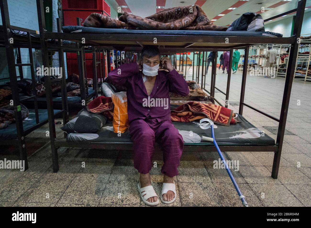 Teheran, Iran. März 2020. Obdachlose Männer, die Gesichtsschutzmasken und saubere Kleidung tragen, werden nach der Desinfektion und dem Duschen im Süden Teherans nach einem neuen Coronavirus (Covid-19) im Iran in Khavaran Obdachlose Obdachlosen gesehen. Die Khavaran-Halle soll 600 Personen beherbergen. Diese Kapazität wird in der Winternacht auf 1.100 ausgedehnt. In der Anlage sind auch Saisonarbeiter untergebracht, die duschen, eine warme Mahlzeit pro Tag essen und dort schlafen. Kredit: Zuma Press, Inc./Alamy Live News Stockfoto