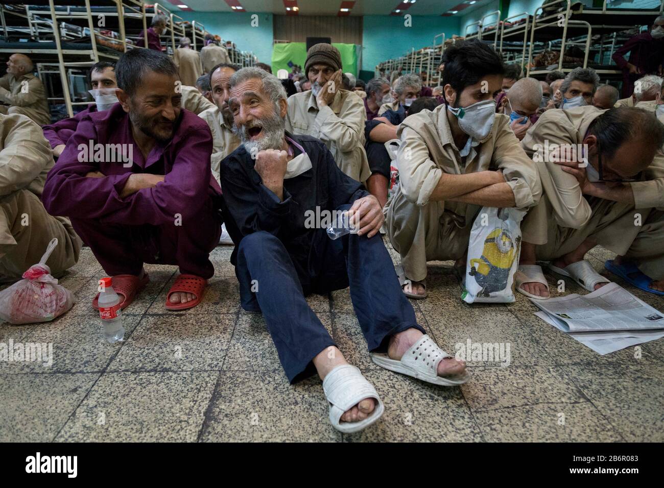Teheran, Iran. März 2020. Obdachlose Männer, die Gesichtsschutzmasken und saubere Kleidung tragen, werden nach der Desinfektion und dem Duschen im Süden Teherans nach einem neuen Coronavirus (Covid-19) im Iran in Khavaran Obdachlose Obdachlosen gesehen. Die Khavaran-Halle soll 600 Personen beherbergen. Diese Kapazität wird in der Winternacht auf 1.100 ausgedehnt. In der Anlage sind auch Saisonarbeiter untergebracht, die duschen, eine warme Mahlzeit pro Tag essen und dort schlafen. Kredit: Zuma Press, Inc./Alamy Live News Stockfoto