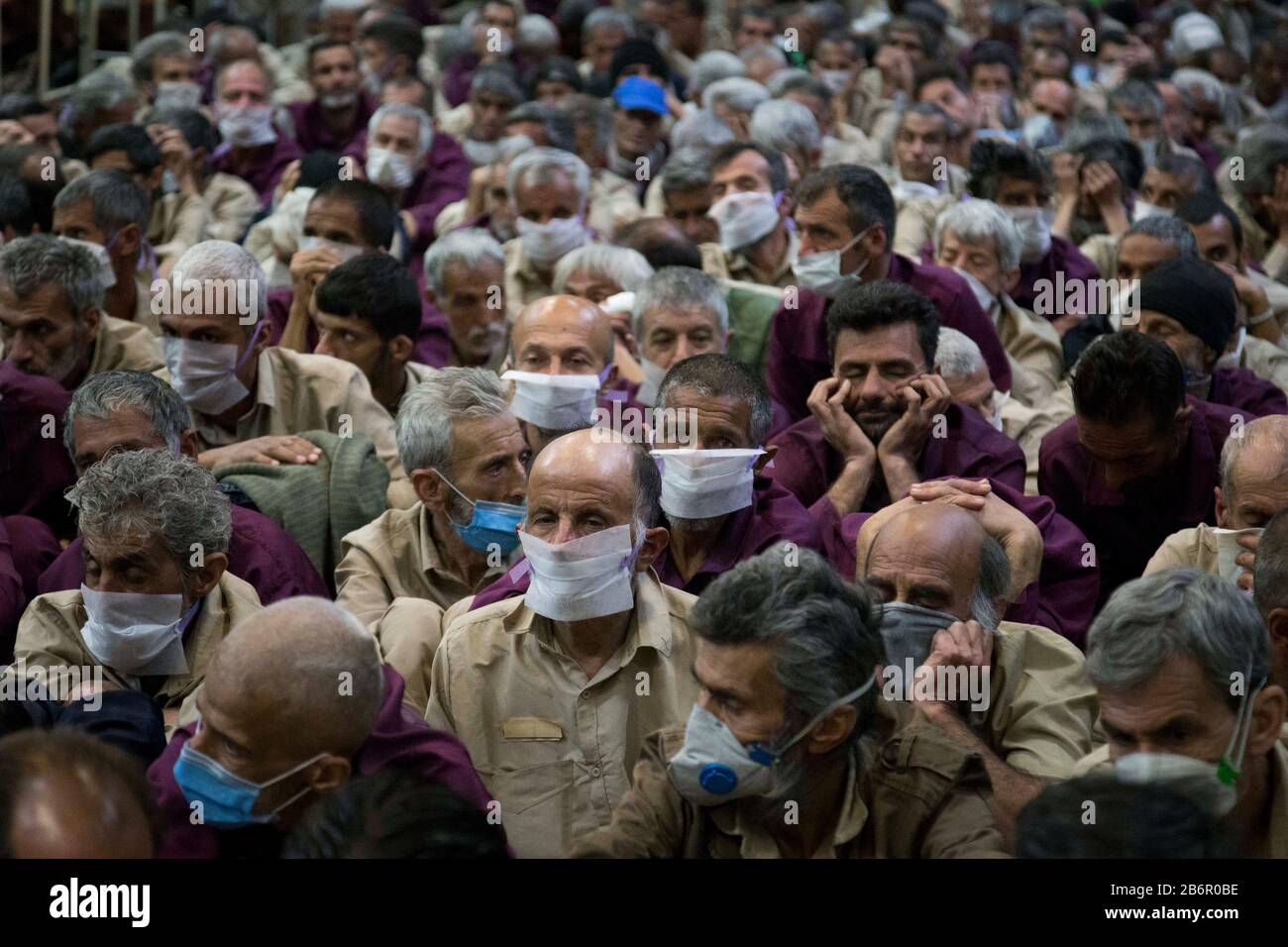 Teheran, Iran. März 2020. Obdachlose Männer, die Gesichtsschutzmasken und saubere Kleidung tragen, werden nach der Desinfektion und dem Duschen im Süden Teherans nach einem neuen Coronavirus (Covid-19) im Iran in Khavaran Obdachlose Obdachlosen gesehen. Die Khavaran-Halle soll 600 Personen beherbergen. Diese Kapazität wird in der Winternacht auf 1.100 ausgedehnt. In der Anlage sind auch Saisonarbeiter untergebracht, die duschen, eine warme Mahlzeit pro Tag essen und dort schlafen. Kredit: Zuma Press, Inc./Alamy Live News Stockfoto