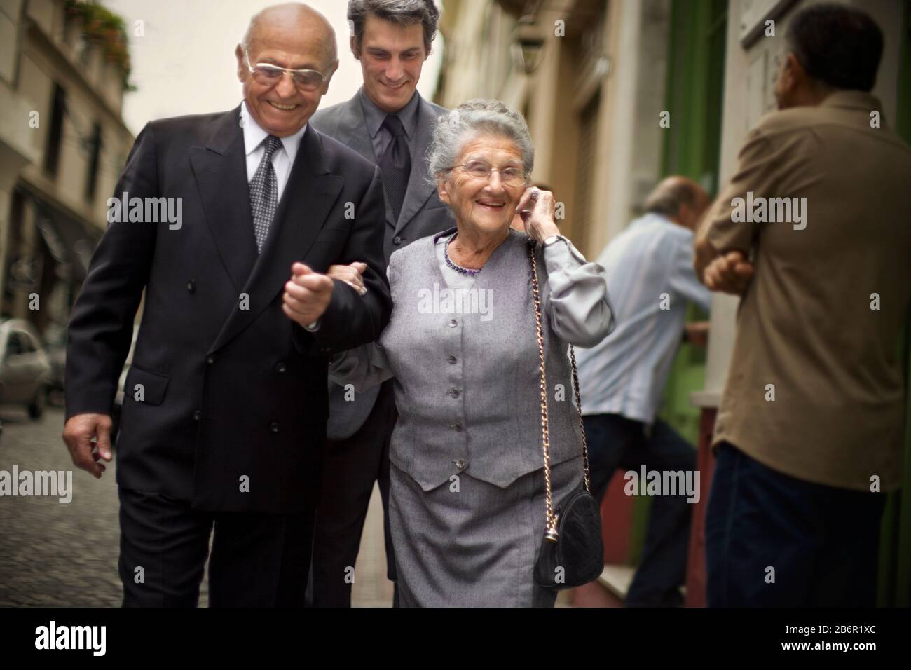 Ein älteres Paar Spaziergänge entlang als Menschen, sie verbindet. Stockfoto