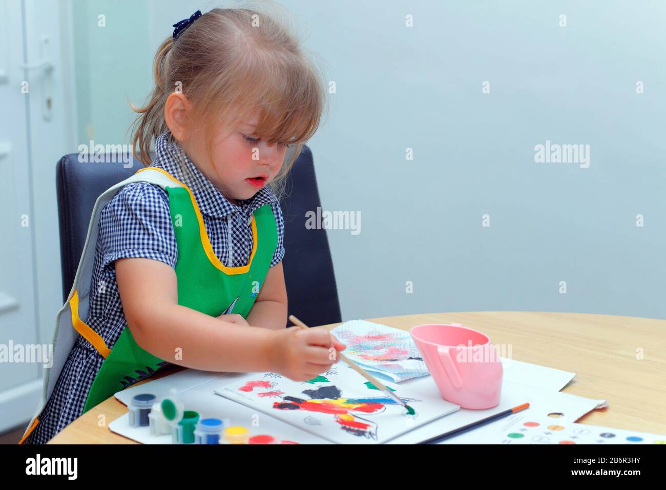 Ein kleines Mädchen, das mit einem Pinsel ein Bild malt Stockfoto