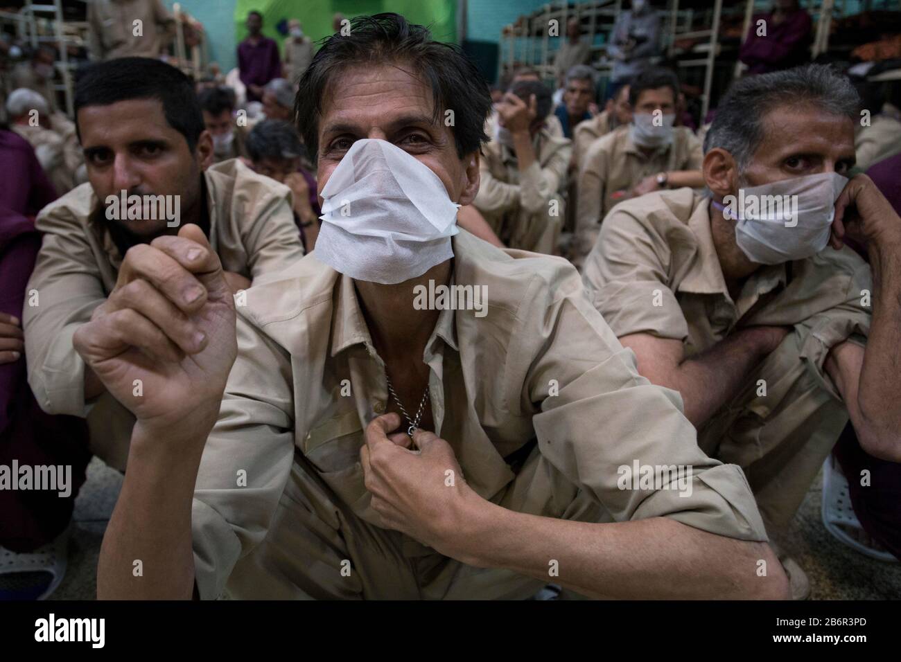 Teheran, Iran. März 2020. Obdachlose Männer, die Gesichtsschutzmasken und saubere Kleidung tragen, werden nach der Desinfektion und dem Duschen im Süden Teherans nach einem neuen Coronavirus (Covid-19) im Iran in Khavaran Obdachlose Obdachlosen gesehen. Die Khavaran-Halle soll 600 Personen beherbergen. Diese Kapazität wird in der Winternacht auf 1.100 ausgedehnt. In der Anlage sind auch Saisonarbeiter untergebracht, die duschen, eine warme Mahlzeit pro Tag essen und dort schlafen. Kredit: Zuma Press, Inc./Alamy Live News Stockfoto