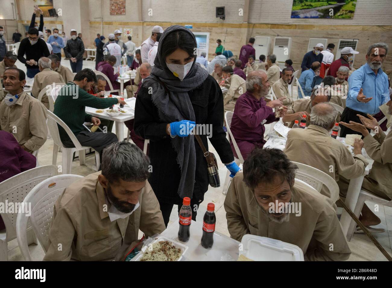 Teheran, Iran. März 2020. Ein Mitglied des iranischen Freiwilligenthebers Red Crescent erklärt obdachlosen Männern, wie sie sich gegen das neue Coronavirus (Covid-19) in Khavaran Obdachlose-Schutzhaus im Süden Teherans nach einem neuen Coronavirus (Covid-19) Ausbruch im Iran schützen können. Die Khavaran-Halle soll 600 Personen beherbergen. Diese Kapazität wird in der Winternacht auf 1.100 ausgedehnt. In der Anlage sind auch Saisonarbeiter untergebracht, die duschen, eine warme Mahlzeit pro Tag essen und dort schlafen. Kredit: Zuma Press, Inc./Alamy Live News Stockfoto