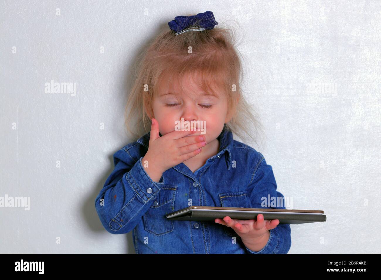 Ein kleines Mädchen, das dumme Gesichter zieht, während sie ihr Tablet verwendet. Stockfoto