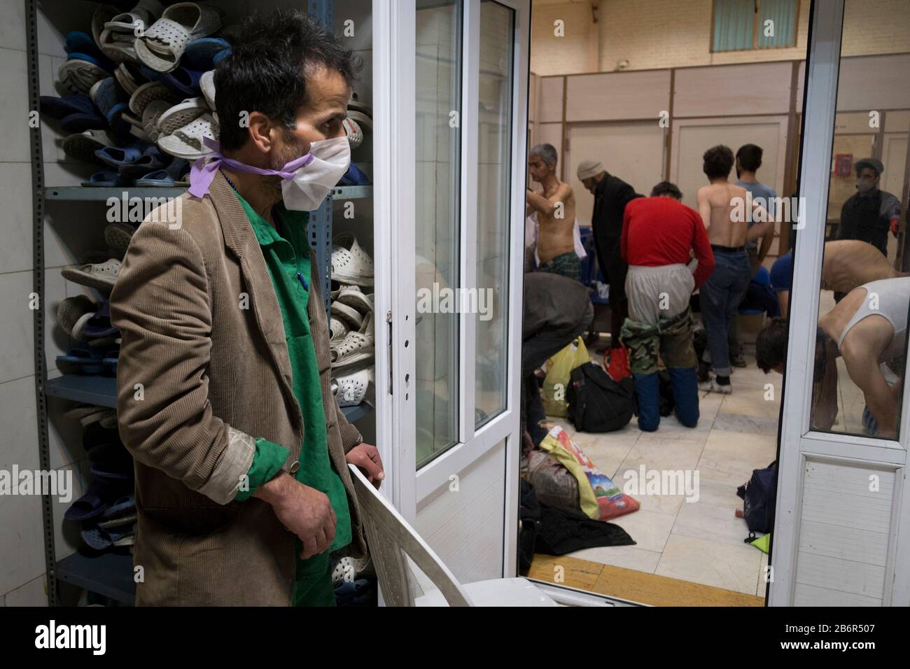 Teheran, Iran. März 2020. Obdachlose Männer entfernen ihre Kleidung, nachdem sie nach einem neuen Ausbruch des Coronavirus (Covid-19) im Iran in Khavaran Obdachlose Shelter im Süden Teherans desinfiziert haben. Die Khavaran-Halle soll 600 Personen beherbergen. Diese Kapazität wird in der Winternacht auf 1.100 ausgedehnt. In der Anlage sind auch Saisonarbeiter untergebracht, die duschen, eine warme Mahlzeit pro Tag essen und dort schlafen. Kredit: Zuma Press, Inc./Alamy Live News Stockfoto