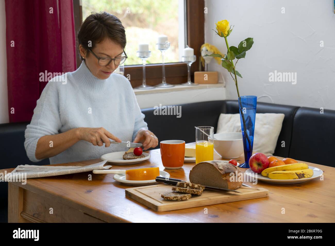 Frau beim Frühstück, zu Hause, gesundes Frühstück, mit Tee, Obst, Vollkornbrot, Müsli, Stockfoto