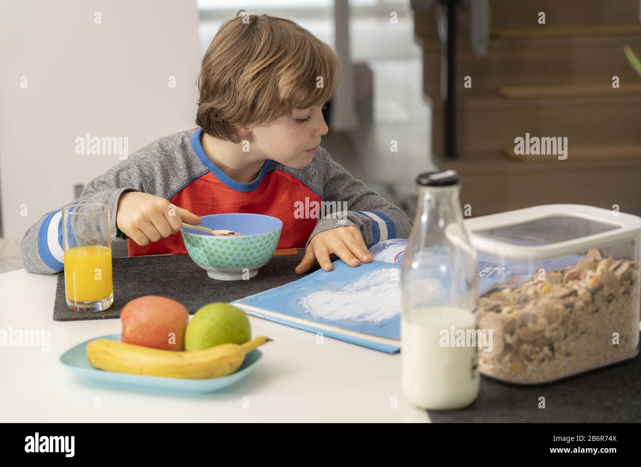 Jung, 9 Jahre alt, zum Frühstück, zu Hause, vor der Schule, gesundes Frühstück, mit Milch, Orangensaft, Obst, Müsli, Stockfoto