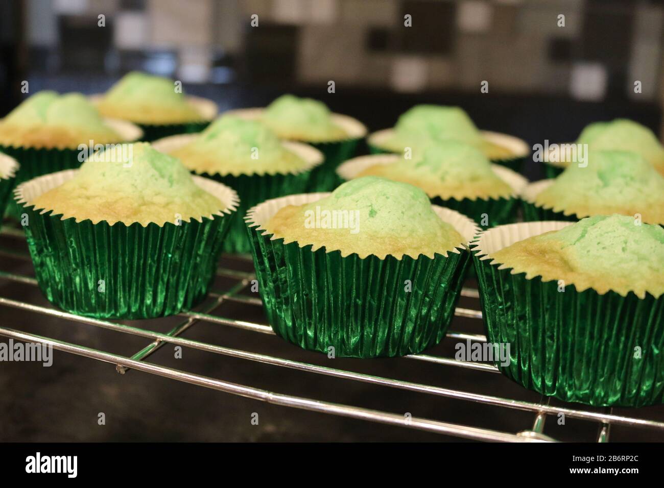 Grüne Cupcakes kühlen auf Drahtgestell, nachdem sie zu Hause im Ofen zur Geburtstagsparty gebacken wurden Stockfoto