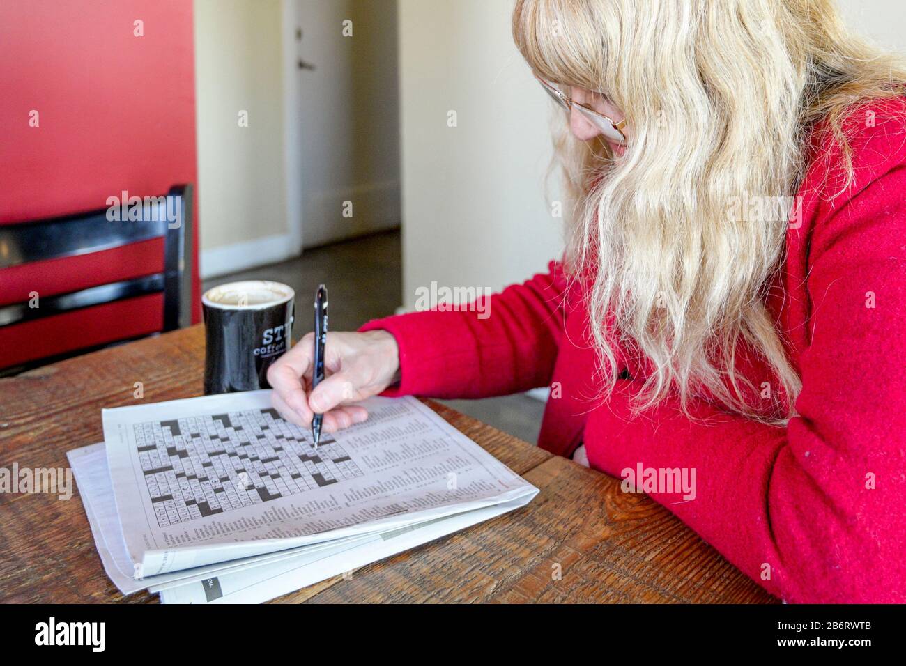 Frau, die Kreuzworträtsel im Café macht Stockfoto