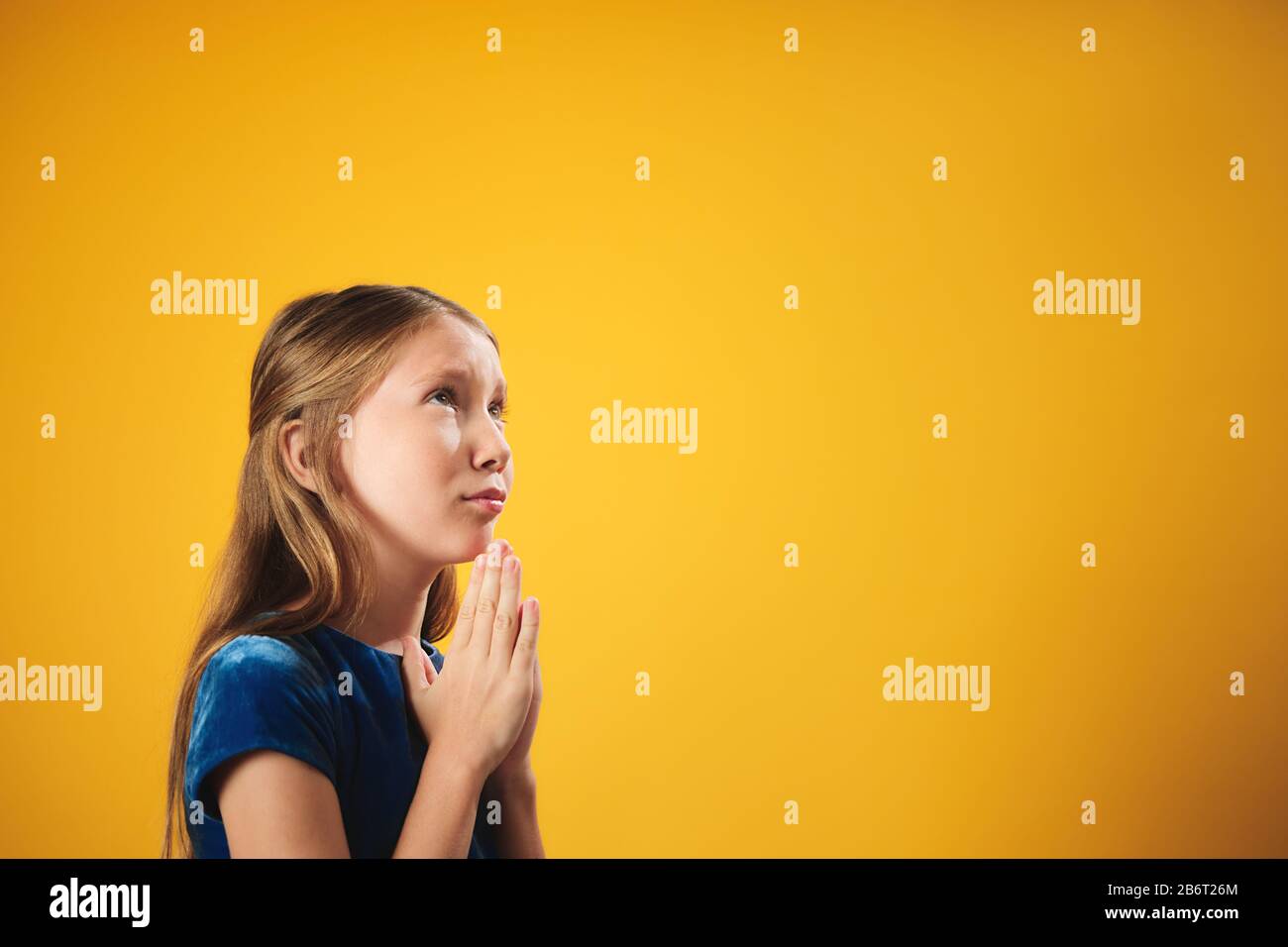 Porträt Des Kaukasischen Kleinen Mädchens, Das Gott Auf Gelbem Hintergrund Betet Stockfoto