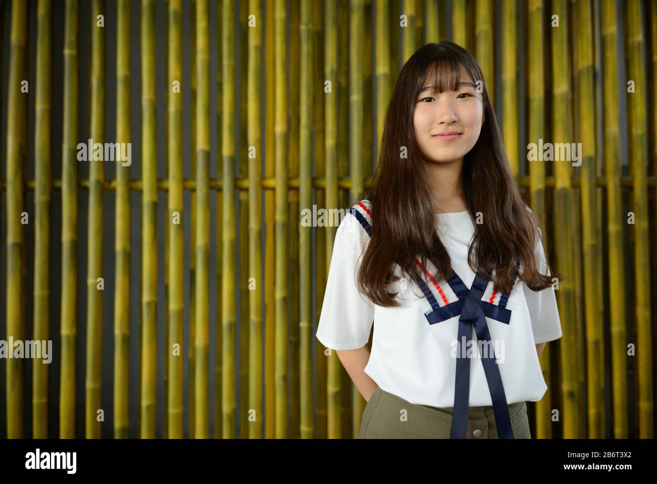 Junge schöne asiatische Teenager-Mädchen gegen Bambuszaun Stockfoto