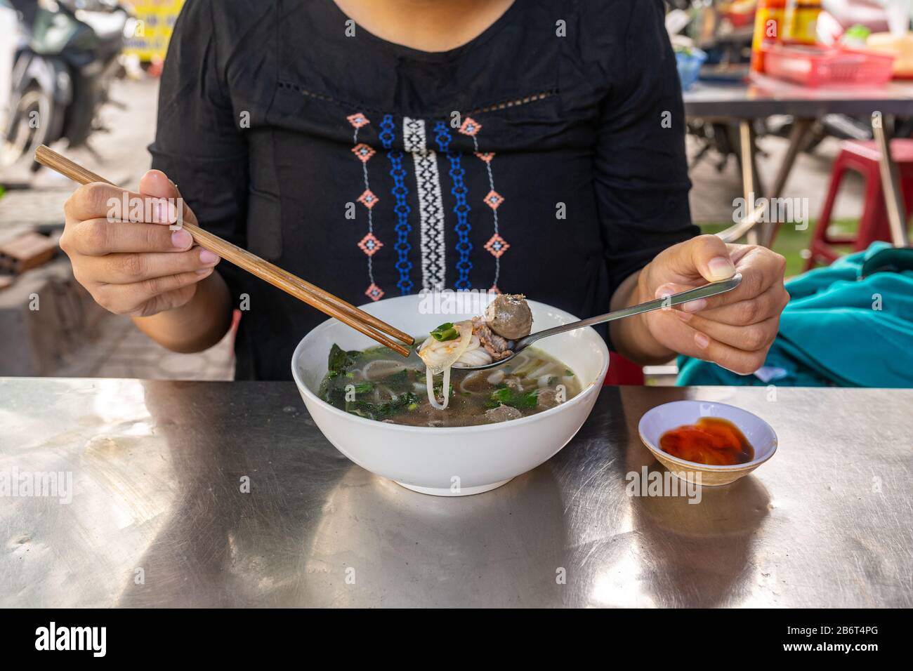 Asiatischer Tourist, der Pho Nudelsuppe mit Essstäbchen und Löffel isst Stockfoto