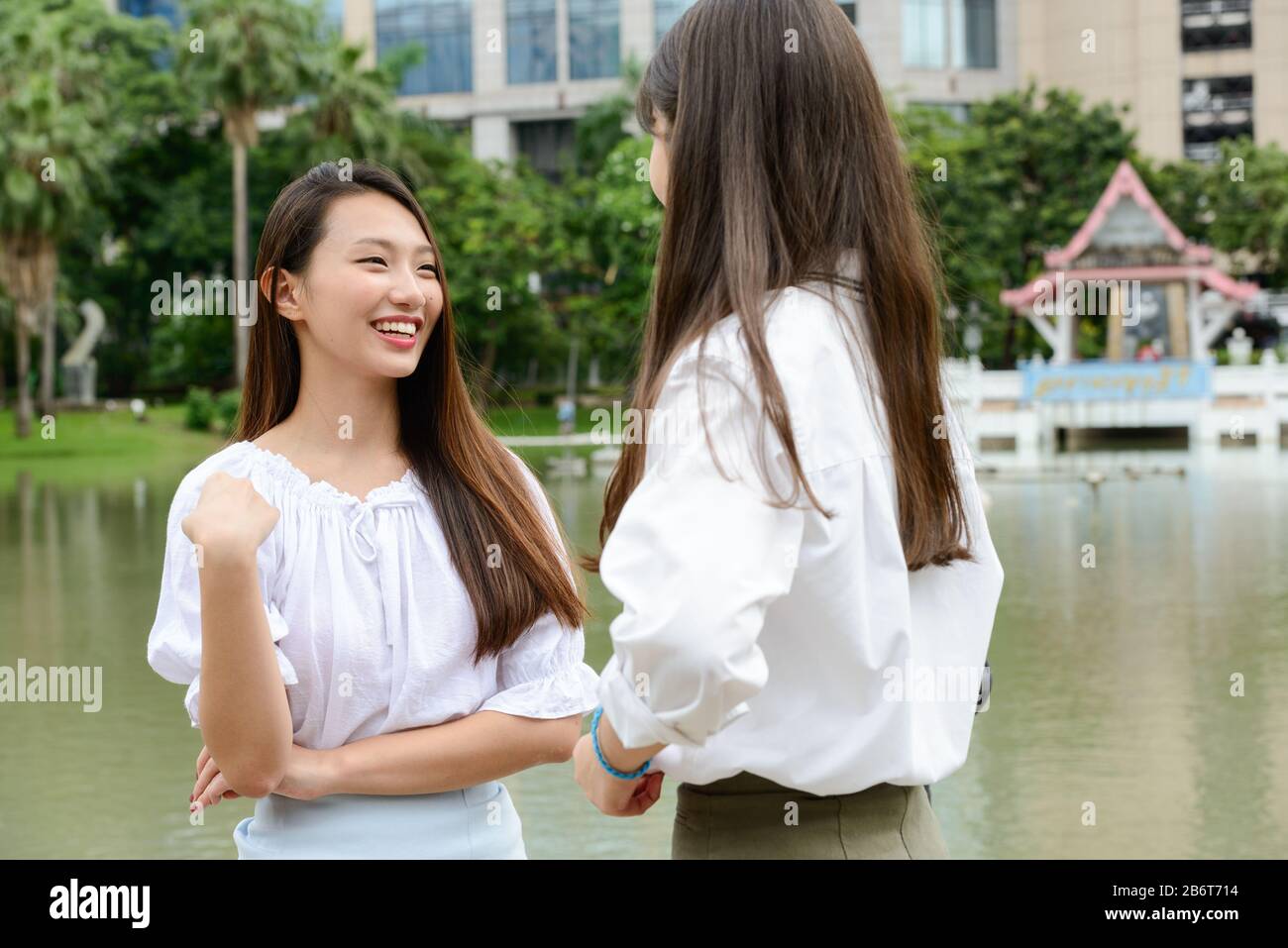 Zwei junge, schöne asiatische Teenager-Mädchen, die im Park sprechen Stockfoto