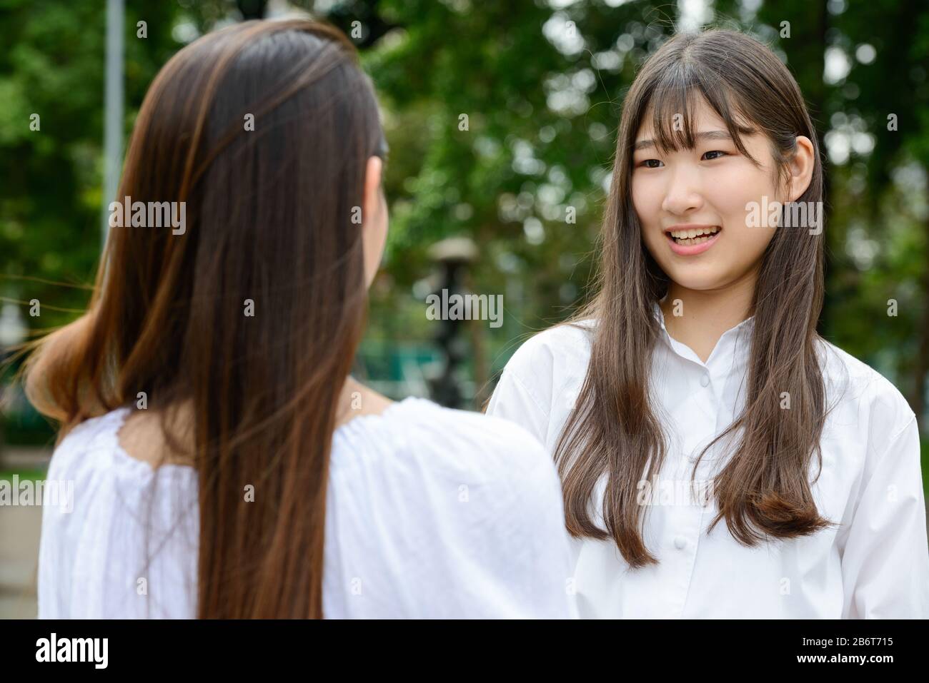 Zwei junge, schöne asiatische Teenager-Mädchen, die im Park sprechen Stockfoto