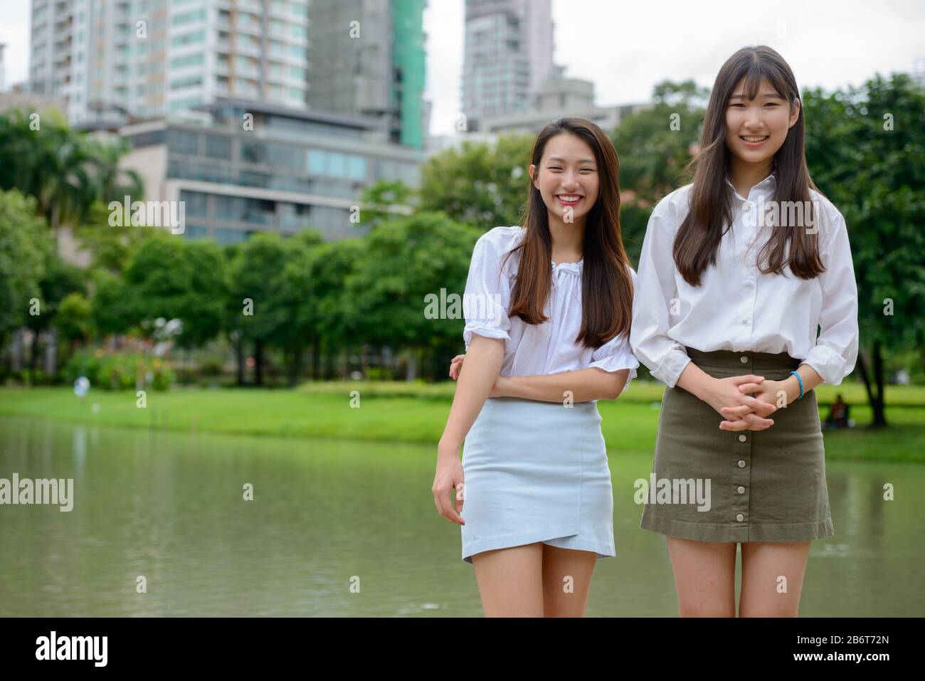 Zwei glückliche junge, schöne asiatische Teenager-Mädchen, die zusammen Spaß am Park haben Stockfoto