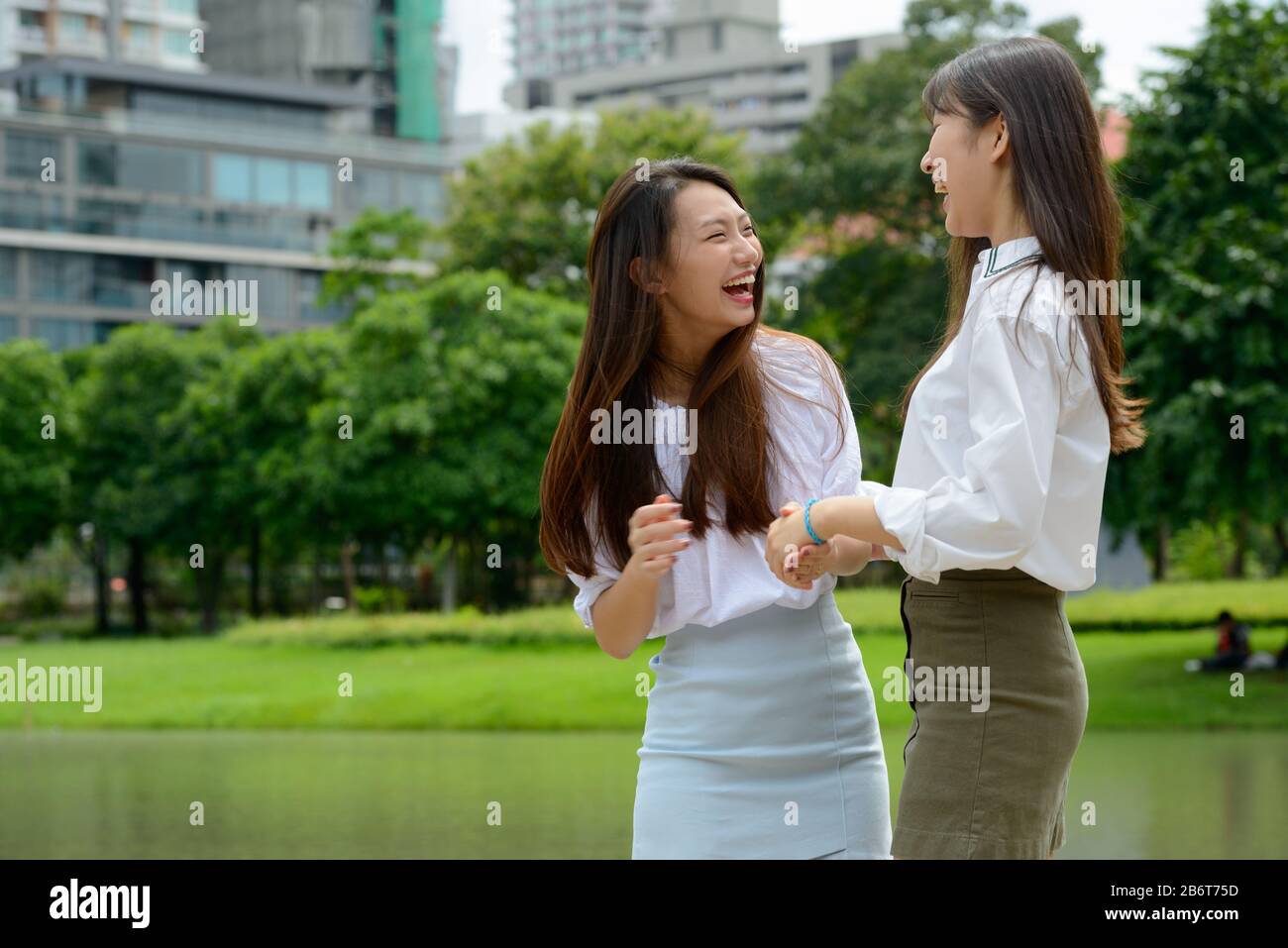 Zwei glückliche junge, schöne asiatische Teenager-Mädchen, die zusammen Spaß am Park haben Stockfoto